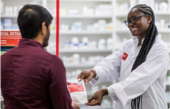 Smiling pharmacist joyfully handing over prescription medicine to customer