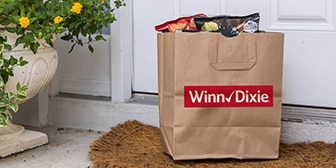 Front doorstep showing a Winn-Dixie grocery paper bag filled with groceries