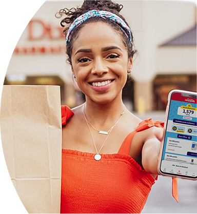 Woman smiling outside of a Winn-Dixie holding a grocery bag and phone with Winn-Dixie app