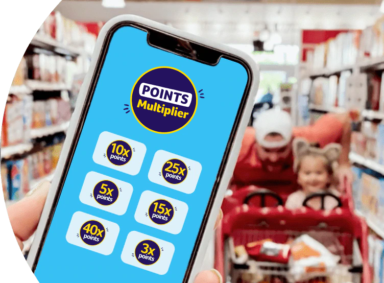 Foreground: Shopper holding a phone with the Points multiplier screen opened. Background: Man joyfully pushing a child in a shopping cart.