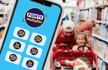 Foreground: Shopper holding a phone with the Points multiplier screen opened. Background: Man joyfully pushing a child in a shopping cart.