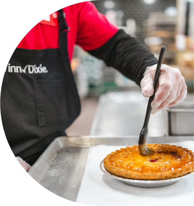 A Winn-Dixie associate in an apron carefully sets a pastry on a plate, showcasing their baking skills in a cozy kitchen environment.