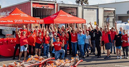 Group of Winn-Dixie gives foundation volunteers joyfully cheering with their arms up.