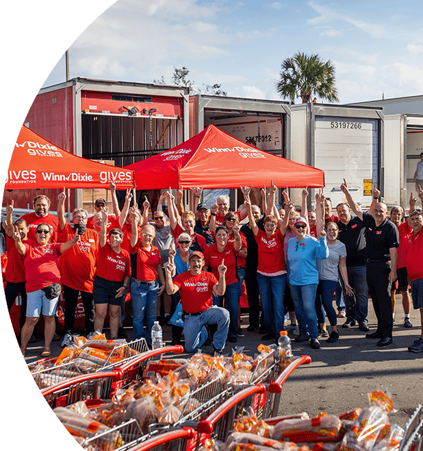 Group of Winn-Dixie gives foundation volunteers joyfully cheering with their arms up.