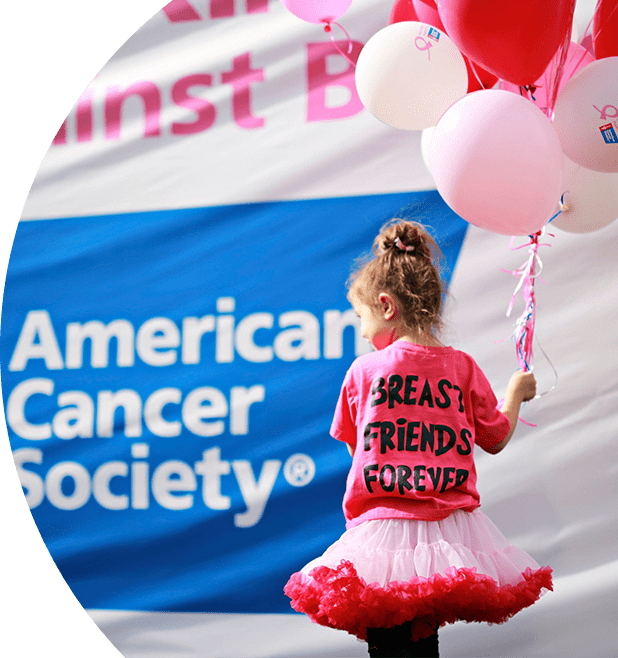 Young girl holding pink balloons. She is wearing a pink tutu and a pink shirt that says "Breast Friends Forever". Behind her there is the American Cancer Society® logo placed on a banner.