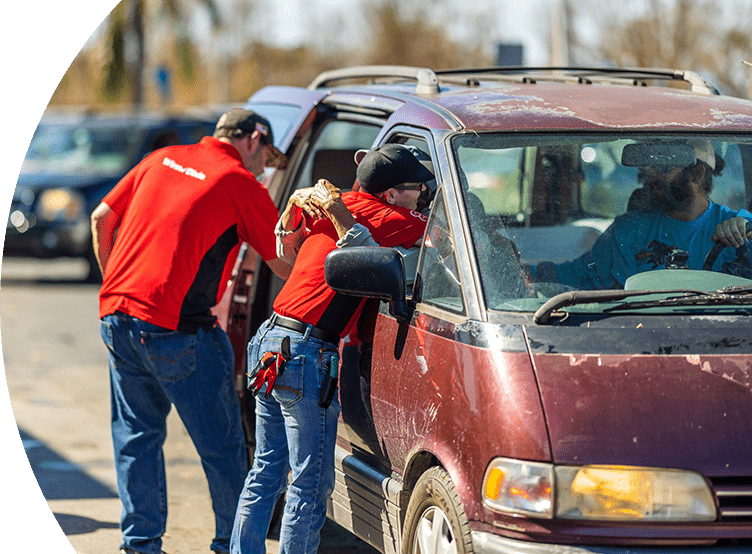 Winn-Dixie associate embracing impacted local resident in car while another associate assists with packing essentials inside the vehicle.
