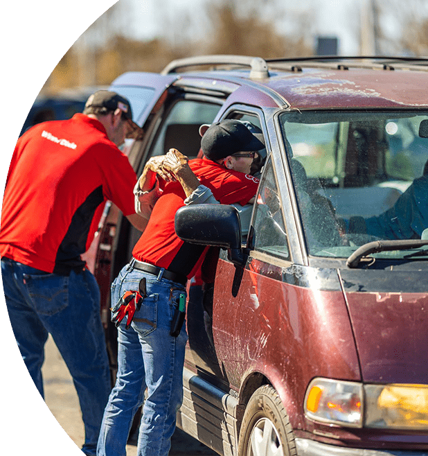 Winn-Dixie associate embracing impacted local resident in car while another associate assists with packing essentials inside the vehicle.