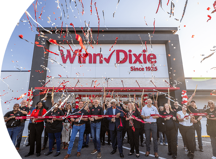 Group of employees outside of a Winn-Dixie celebrating a grand opening with confetti in the air