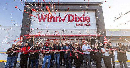 Group of employees outside of a Winn-Dixie celebrating a grand opening with confetti in the air