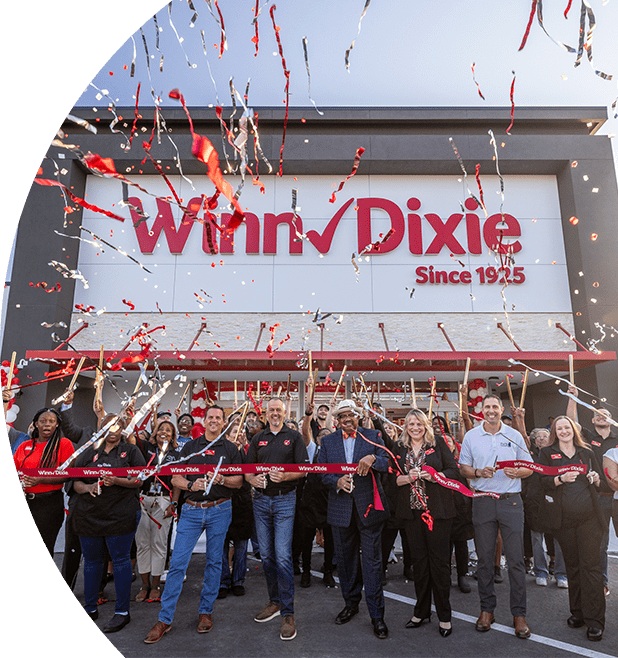 Group of employees outside of a Winn-Dixie celebrating a grand opening with confetti in the air