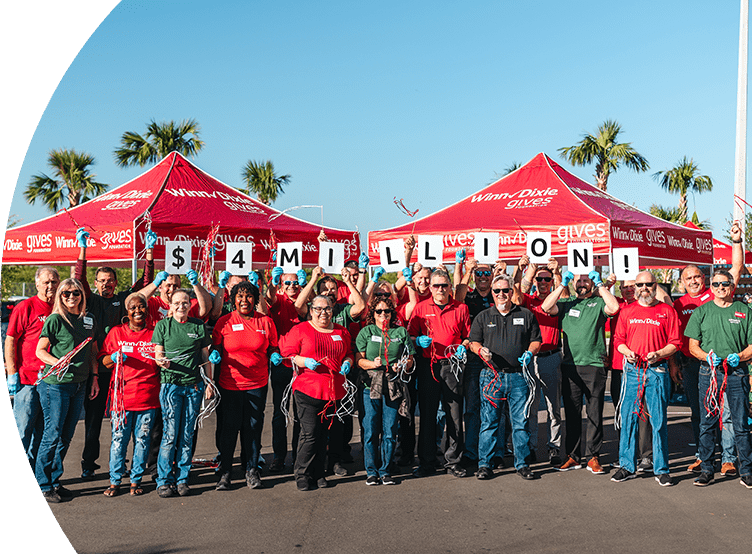 Group of happy Southeastern Grocers' employees holding up signs that read $4 million