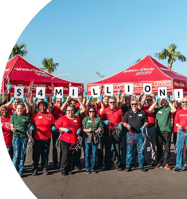 Group of happy Southeastern Grocers' employees holding up signs that read $4 million
