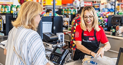 Winn-Dixie cashier joyfully bagging grocery items for a customer.