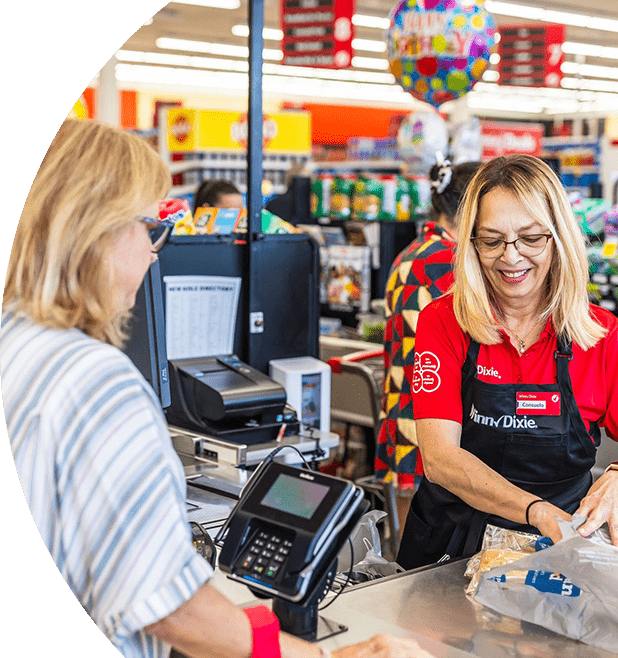 Winn-Dixie cashier joyfully bagging grocery items for a customer.