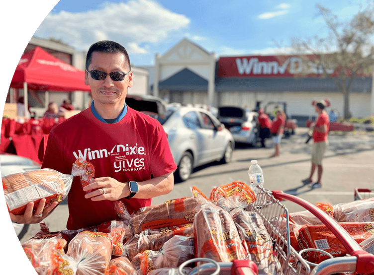 Raymond Rhee, Chief People Officer for Southeastern Grocers, wearing a Winn-Dixie Gives Foundation shirt. He is smiling while organizing food donations.