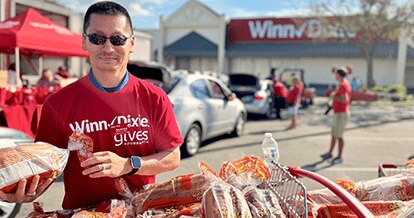 Raymond Rhee, Chief People Officer for Southeastern Grocers, wearing a Winn-Dixie Gives Foundation shirt. He is smiling while organizing food donations.