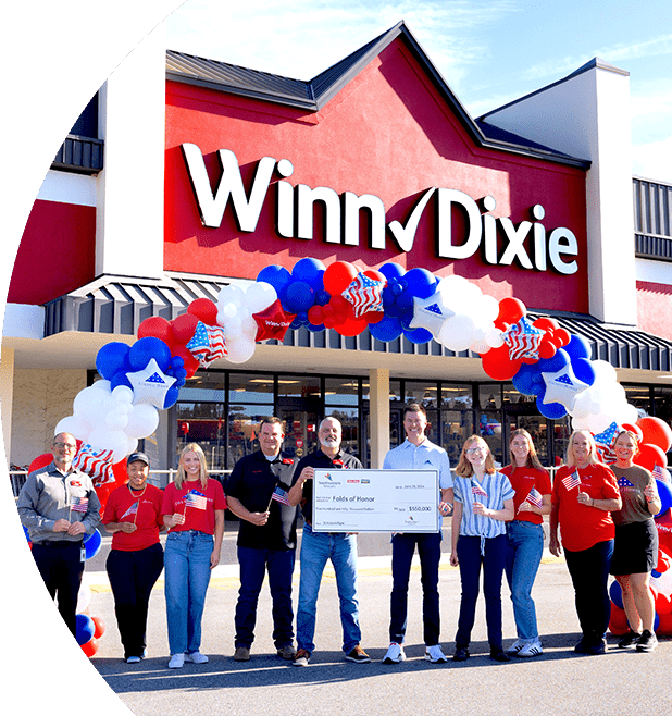 Group of SEG employees standing in front of a Winn-Dixie holding a large check.