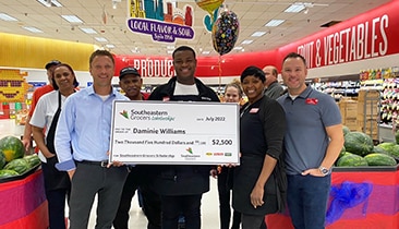 Group of Winn-Dixie employees smiling while one holds a big check.