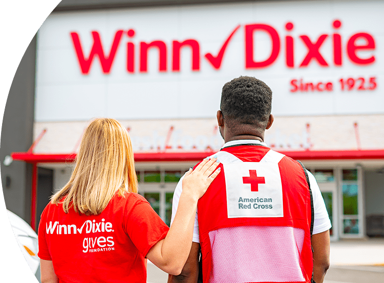 Winn-Dixie female employee with hand on male American Red Cross volunteer's shoulder. Looking towards the outside of a Winn-Dixie.