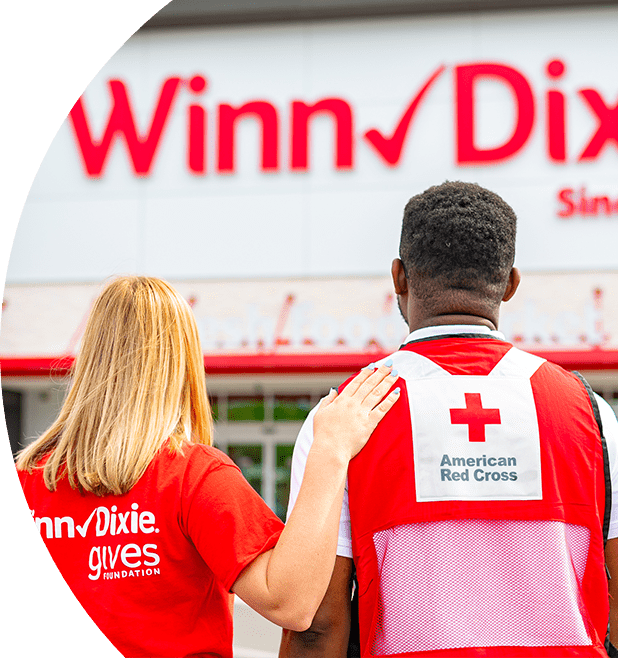 Winn-Dixie female employee with hand on male American Red Cross volunteer's shoulder. Looking towards the outside of a Winn-Dixie.