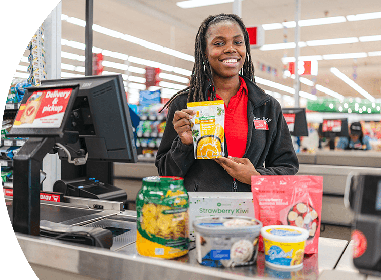 Smiling female Winn-Dixie cashier at check out with award-winning Own Brand products.