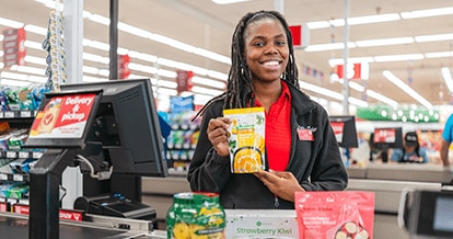 Smiling female Winn-Dixie cashier at check out with award-winning Own Brand products.