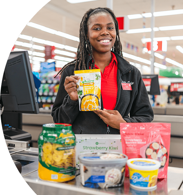 Smiling female Winn-Dixie cashier at check out with award-winning Own Brand products.
