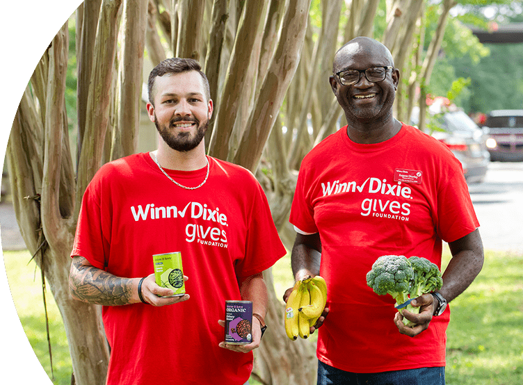 Gives Foundation volunteers joyfully holding canned goods and produce.