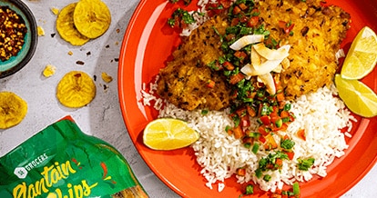 Plantain-crusted cod with coconut rice served on a plate. Next to the plate, there is a container of SE Grocers plantain chips.