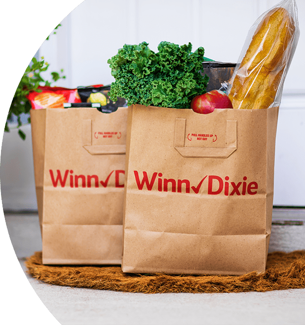 Two produce-filled Winn-Dixie paper bags sitting on a doorstep