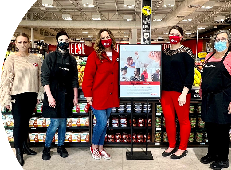 Image of 4 employees in a Winn-Dixie store next to an American Heart Association poster. 