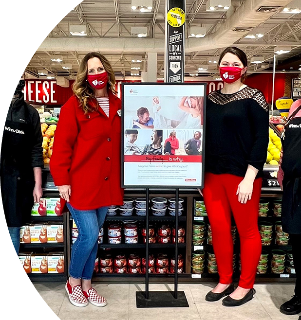 Image of 4 employees in a Winn-Dixie store next to an American Heart Association poster.