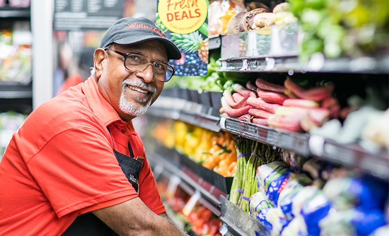 Winn-Dixie associate stocking produce and smiling