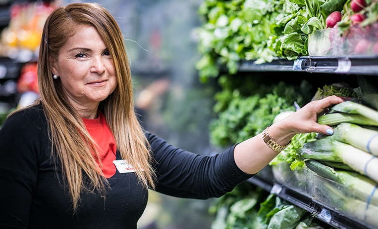 Winn-Dixie associate smiling and stocking produce