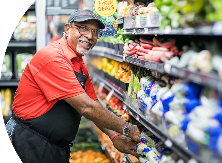 Winn-Dixie employee smiling putting produce away.