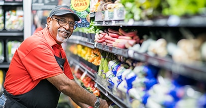 Winn-Dixie employee smiling putting produce away.