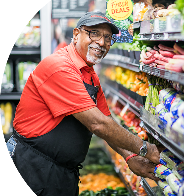 Winn-Dixie employee smiling putting produce away.