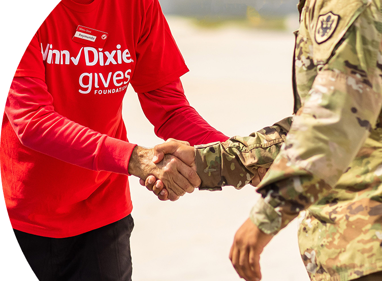 Individual wearing a Winn-Dixie gives Foundation shirt giving a handshake to a military service member in uniform.
