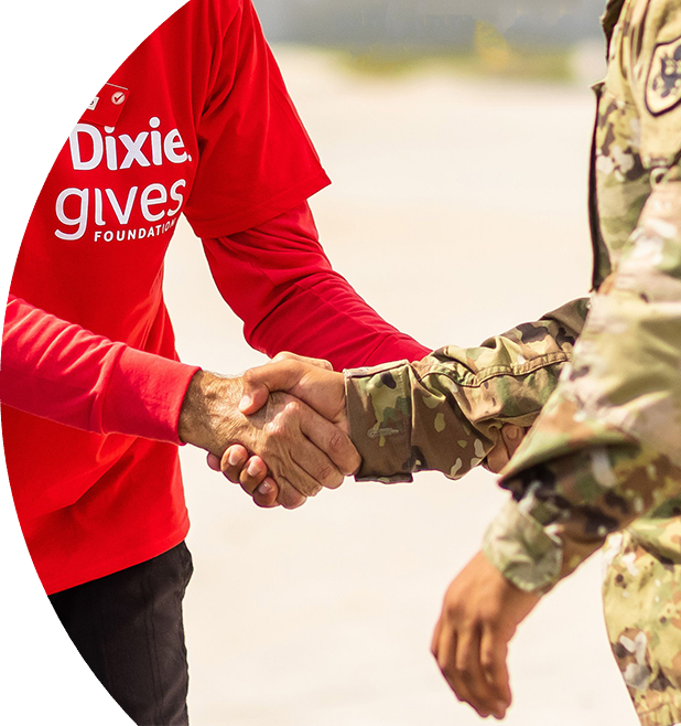 Individual wearing a Winn-Dixie gives Foundation shirt giving a handshake to a military service member in uniform.