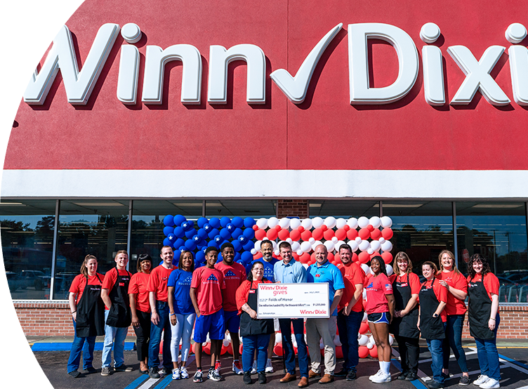 Group of people standing in front of a Winn-Dixie holding a Winn-Dixie gives jumbo check for Folds of Honor